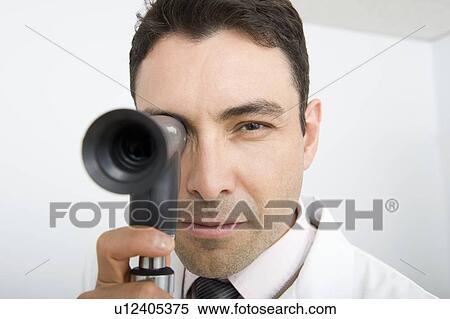 Stock Photography - Optician looks through sight testing equipment. Fotosearch