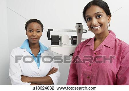 Stock Image - Portarit of female doctor and patient, scales in background. Fotosearch