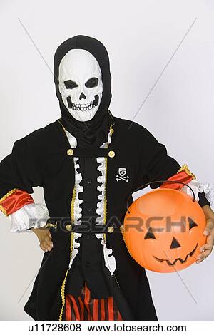 Stock Photo - Portrait of boy (7-9) wearing skeleton mask, with jack-o-lantern. Fotosearch