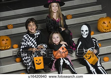 Stock Image - Portrait of boys and girls (7-9) wearing Halloween costumes on steps. Fotosearch
