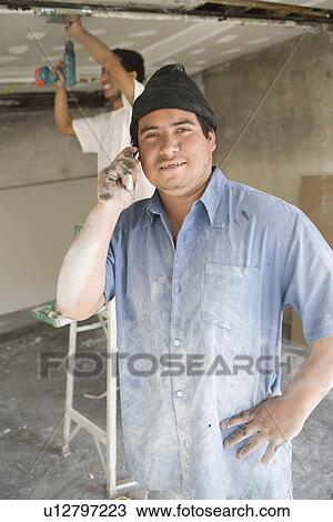 Stock Image - Portrait of construction worker using mobile phone. Fotosearch