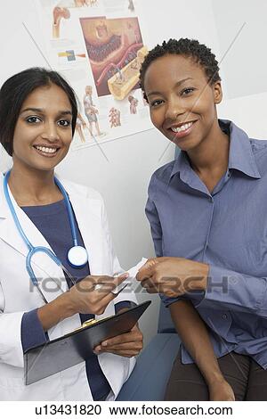 Stock Image - Portrait of female doctor and patient smiling. Fotosearch