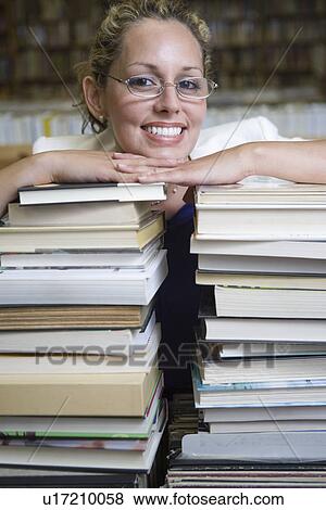 Stock Photo - Portrait of female librarian with stacked books. Fotosearch