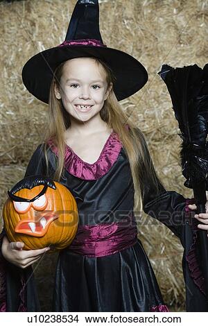 Picture - Portrait of girl (7-9) wearing witch costume by hay. Fotosearch