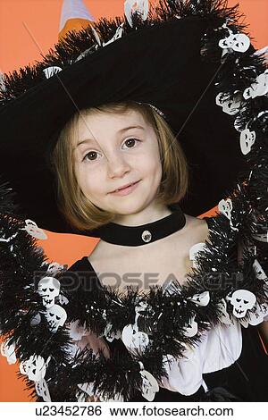 Stock Photograph - Portrait of girl (7-9) wearing witch costume for Halloween. Fotosearch