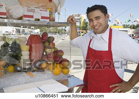 Stock Image - Portrait of male street vendor holding fruit salad. Fotosearch