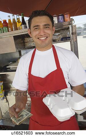 Stock Image - Portrait of male street vendor holding food. Fotosearch