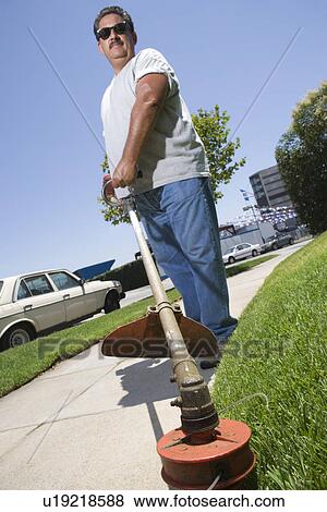 Stock Photo - Portrait of man cutting grass. Fotosearch