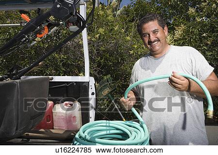 Portrait of man holding hose in garden View Large Photo Image Stock Photography - Portrait of man holding hose in garden. Fotosearch