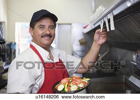 Stock Photograph - Portrait of man working in restaurant kitchen. Fotosearch