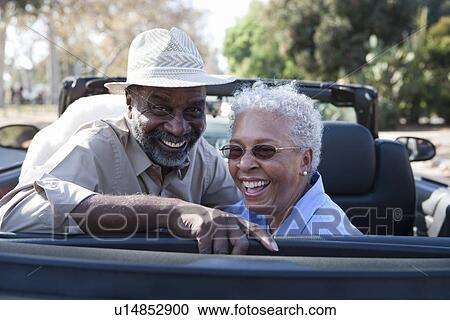 Stock Image - Portrait of senior couple at the back seat of car, smiling. Fotosearch