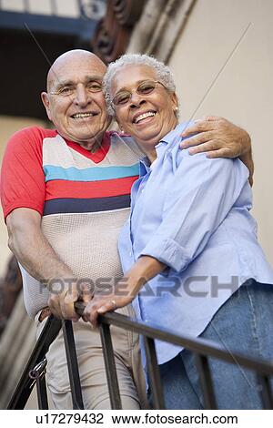 Stock Image - Portrait of senior couple embracing, low angle view. Fotosearch