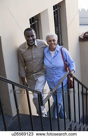 Stock Image - Portrait of senior couple walking up steps, smiling. Fotosearch