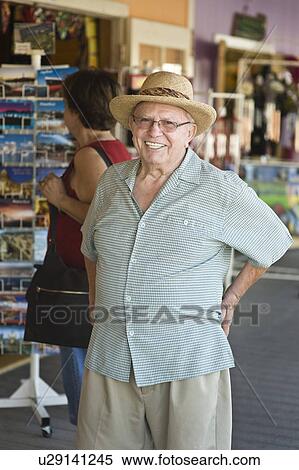Stock Photography - Portrait of senior man standing by souvenir stand. Fotosearch