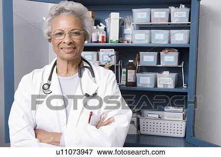 Stock Photo - Portrait of senior medical practitioner and medicine cabinet. Fotosearch