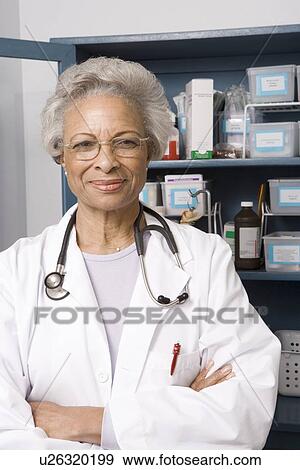 Stock Photo - Portrait of senior medical practitioner and medicine cabinet. Fotosearch