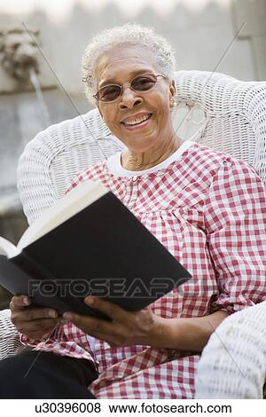Stock Photo - Portrait of senior woman holding book, smiling. Fotosearch
