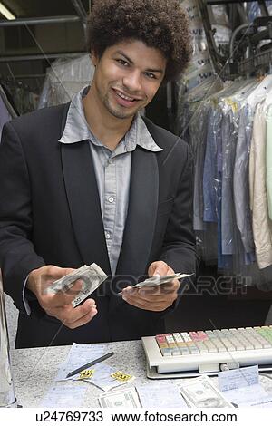 Stock Image - Portrait of young man working in dry cleaners. Fotosearch