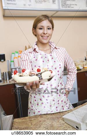 Stock Photography - Portrait of young woman serving ice cream. Fotosearch