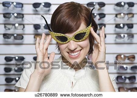Stock Photo - Portrait of young woman swearing glasses in shop. Fotosearch