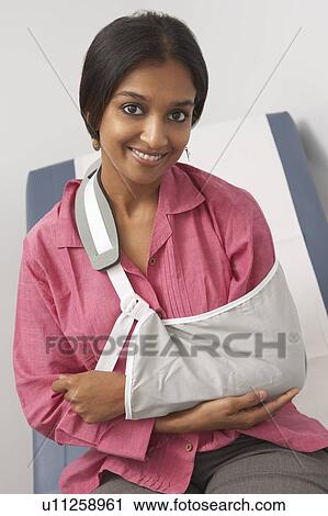 Stock Image - Portrait of young woman with arm in sling. Fotosearch