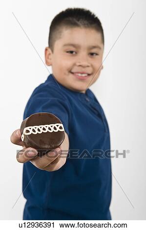 Stock Image - Pre-teen (10-12) boy holding out cookie. Fotosearch