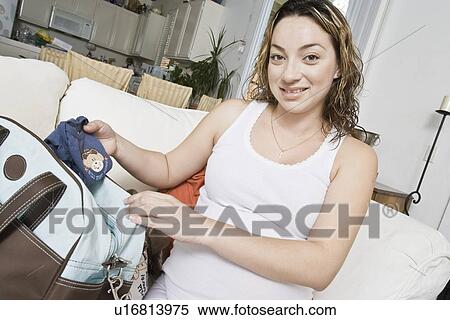 Stock Photography - Pregnant woman packing baby clothes. Fotosearch