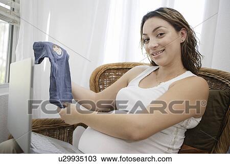 Pregnant woman with laptop holing baby clothing View Large Photo Image Stock Image - Pregnant woman with laptop holing baby clothing. Fotosearch