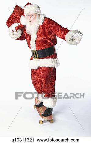 Stock Image - Santa Claus on skateboard carrying sack. Fotosearch