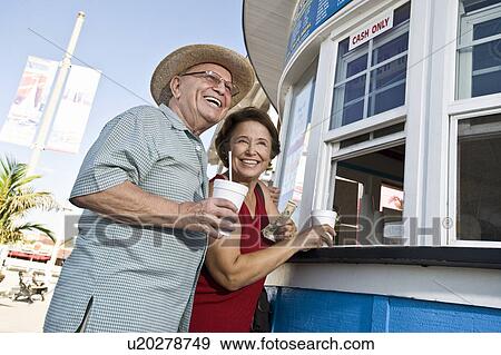 Stock Photo - Senior couple buying drinks at food stand. Fotosearch