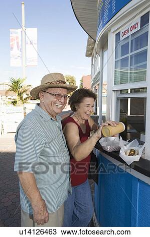 Senior couple buying hot dogs at food stand View Large Photo Image Stock Image - Senior couple buying hot dogs at food stand. Fotosearch