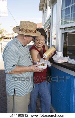 Senior couple buying hot dogs at food stand View Large Photo Image Stock Image - Senior couple buying hot dogs at food stand. Fotosearch