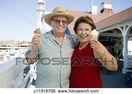 Stock Photograph - Senior couple holding ice creams. Fotosearch