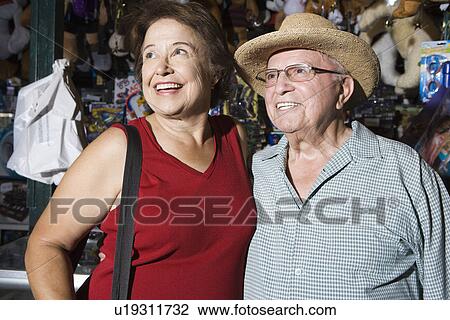 Stock Image - Senior couple in souvenir shop, smiling. Fotosearch