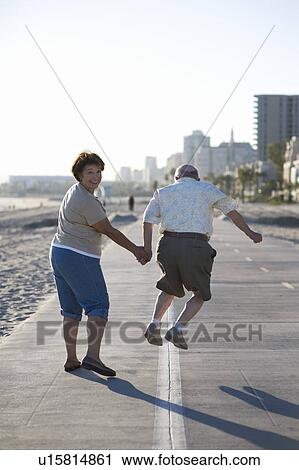 Stock Image - Senior couple on footpath along beach. Fotosearch