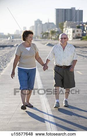 Stock Photo - Senior couple on footpath along beach. Fotosearch