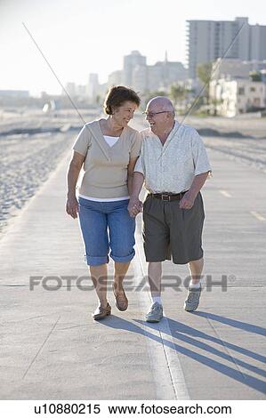 Stock Photography - Senior couple on footpath along beach. Fotosearch