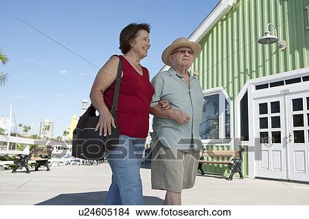 Picture - Senior couple on vacations, walking arm in arm. Fotosearch