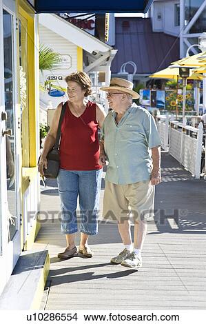 Picture - Senior couple on vacations watching window displays. Fotosearch