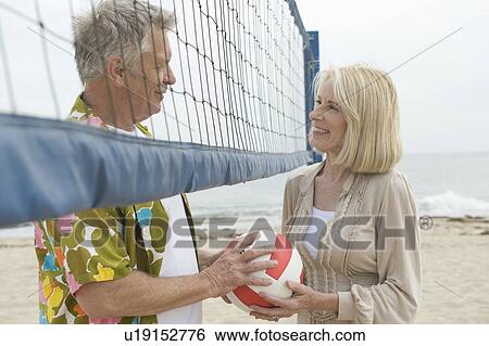 Stock Photograph - Senior couple stand at volleyball net. Fotosearch