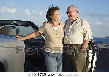 Senior couple standing in front of car View Large Photo Image Stock Photo - Senior couple standing in front of car. Fotosearch