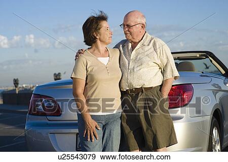 Senior couple standing in front of car View Large Photo Image Stock Photo - Senior couple standing in front of car. Fotosearch