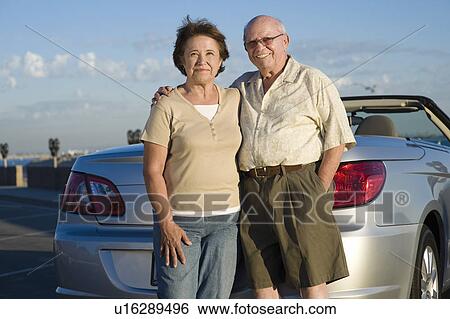Stock Photograph - Senior couple standing in front of car, portrait. Fotosearch
