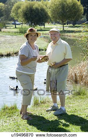 Stock Image - Senior couple standing on lawn, portrait. Fotosearch