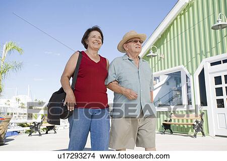 Picture - Senior couple walking on town square, low angle view. Fotosearch