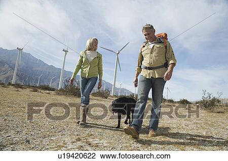Senior couple walking with dog near wind farm View Large Photo Image Stock Image - Senior couple walking with dog near wind farm. Fotosearch