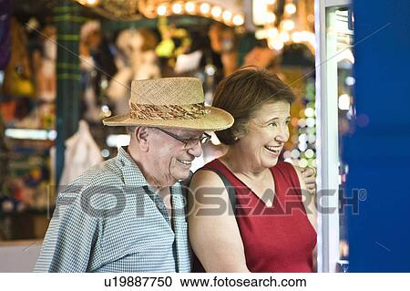 Stock Image - Senior couple watching window display, smiling. Fotosearch