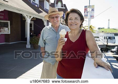 Stock Image - Senior couple, woman eating ice cream. Fotosearch