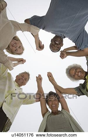 Senior friends hold hands and look down at camera View Large Photo Image Stock Photograph - Senior friends hold hands and look down at camera. Fotosearch