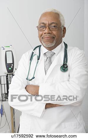 Stock Image - Senior healthcare professional stands with arms folded. Fotosearch
